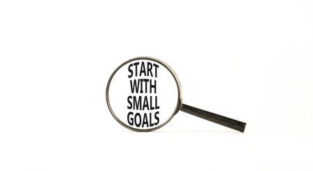 Start with small goals symbol. Concept words phrase Start with small goals in beautiful black magnifying glass. Beautiful white background. Business Start with small goals concept. Copy space.の写真素材