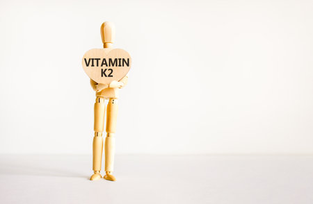Vitamin K2 phylloquinone symbol. Concept words Vitamin K2 on beautiful wooden heart. Doctor's model. Beautiful white background. Copy space. Medical healthy lifestyle Vitamin K2 phylloquinone concept.の写真素材