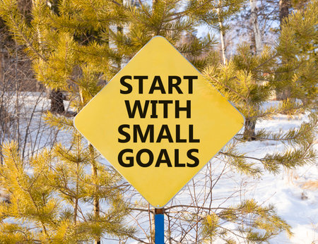 Start with small goals symbol. Concept words phrase Start with small goals on beautiful yellow road sign. Beautiful winter forest background. Business Start with small goals concept. Copy space.の写真素材