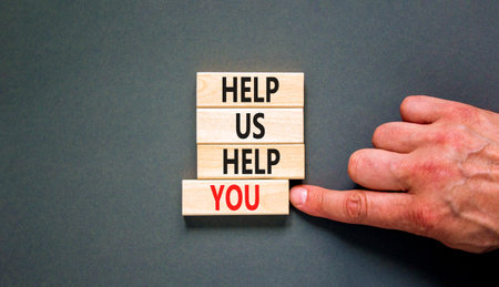 Help you symbol. Concept words phrase Help us help you on beautiful wooden blocks. Beautiful gray paper background. Businessman's hand. Business Help you concept. Copy space.の写真素材