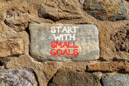Start with small goals symbol. Concept words phrase Start with small goals on beautiful gray stone wall. Beautiful stone wall background. Business Start with small goals concept. Copy space.の写真素材