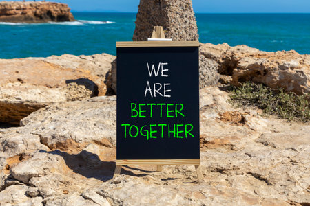 We are better together symbol. Concept words phrase We are better together on beautiful black blackboard. Beautiful stone blue sea sky background. Business We are better together concept. Copy space.の写真素材