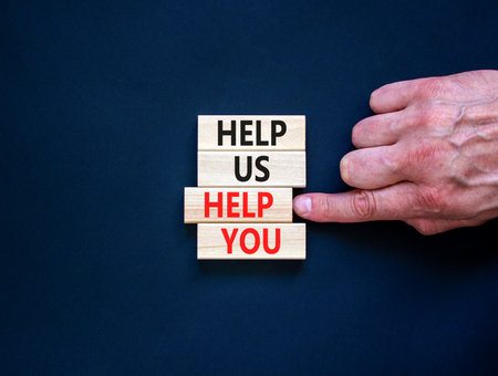 Help you symbol. Concept words phrase Help us help you on beautiful wooden blocks. Beautiful black paper background. Businessman's hand. Business Help you concept. Copy space.の写真素材