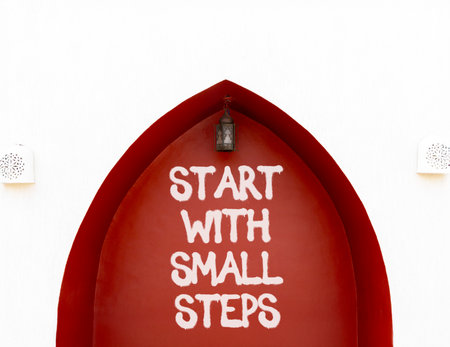Start with small steps symbol. Concept words phrase Start with small steps on beautiful brown wall. Beautiful white wall background. Business Start with small steps concept. Copy space.の写真素材