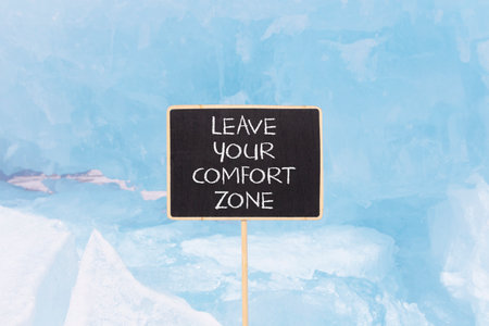 Leave your comfort zone symbol. Concept words Leave your comfort zone on beautiful black blackboard. Beautiful blue ice background. Business psychological Leave your comfort zone concept. Copy space.の写真素材