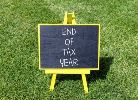 End of tax year symbol. Concept words phrase End of tax year on beautiful black blackboard. Beautiful green grass lawn background. Business End of tax year concept. Copy space.の写真素材