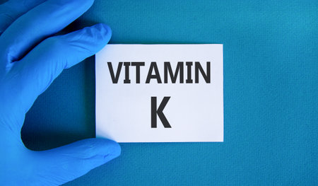 Vitamin K phylloquinone symbol. Concept words Vitamin K on beautiful white card. Doctor's hand blue medical glove. Beautiful blue background. Medical healthy lifestyle Vitamin K phylloquinone concept.の写真素材