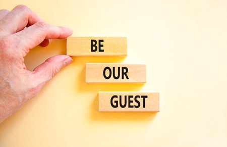Be our guest symbol. Concept words Be our guest on beautiful wooden block. Businessman's hand. Beautiful white background. Business and be our guest concept. Copy space.の写真素材