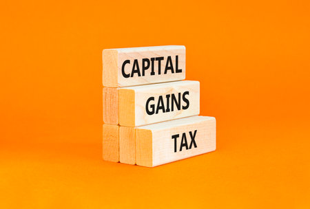 Capital gains tax symbol. Concept words Capital gains tax on beautiful wooden block. Beautiful orange table orange background. Business and capital gains tax concept. Copy space.の写真素材