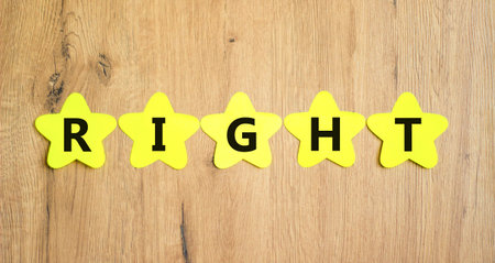 Right symbol. Concept word Right on beautiful yellow paper stars. Beautiful wooden table wooden...