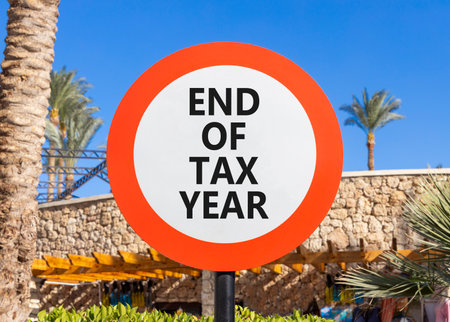 End of tax year symbol. Concept words phrase End of tax year on beautiful road sign. Beautiful palm tree and blue sky background. Business End of tax year concept. Copy space.の写真素材