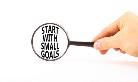 Start with small goals symbol. Concept words phrase Start with small goals in beautiful black magnifying glass. Beautiful white background. Business Start with small goals concept. Copy space.の写真素材