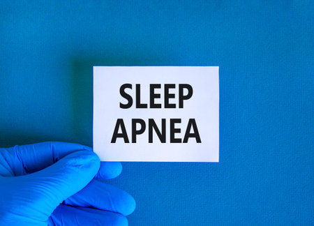 Sleep apnea symbol. Concept words Sleep apnea on beautiful white card. Doctor's hand in blue medical glove. Beautiful blue background. Medical healthy lifestyle sleep apnea concept.の写真素材