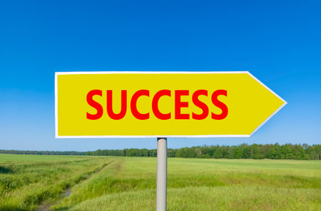 Success symbol. Concept word Success on beautiful yellow road sign. Beautiful blue sky green grass and forest peaceful nature background. Business success concept. Copy space.の写真素材