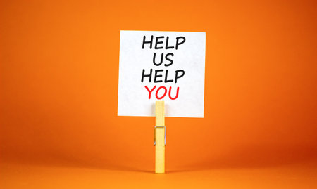Help you symbol. Concept words phrase Help us help you on beautiful white paper on wooden clothespin. Beautiful orange paper background. Business Help you concept. Copy space.の写真素材