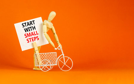 Start with small steps symbol. Concept words phrase Start with small steps on beautiful white paper on clothespin. Beautiful orange background. Business Start with small steps concept. Copy space.の写真素材