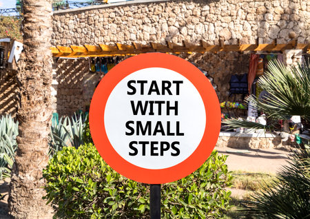 Start with small steps symbol. Concept words phrase Start with small steps on beautiful road sign. Beautiful palm tree background. Business Start with small steps concept. Copy space.の写真素材