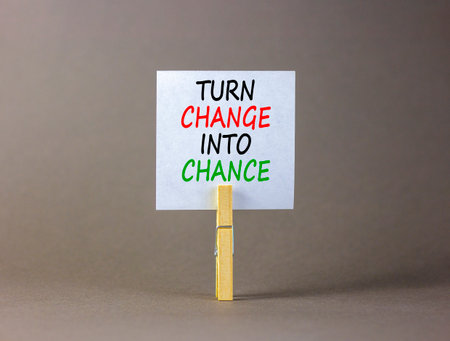 Turn change into chance symbol. Concept words phrase Turn change into chance on beautiful white paper on clothespin. Beautiful gray background. Business Turn change into chance concept. Copy space.の写真素材