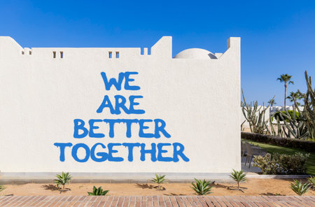 We are better together symbol. Concept words phrase We are better together on beautiful white wall. Beautiful white wall and blue sky background. Business We are better together concept. Copy space.の写真素材