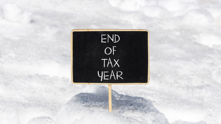 End of tax year symbol. Concept words phrase End of tax year on beautiful black blackboard. Beautiful white snow background. Business End of tax year concept. Copy space.の写真素材