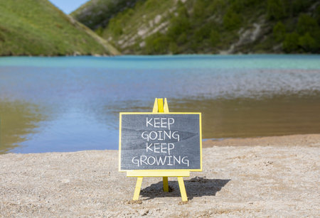 Keep going and growing symbol. Concept words phrase Keep going keep growing on beautiful black blackboard. Beautiful mountain lake background. Business Keep going and growing concept. Copy space.の写真素材