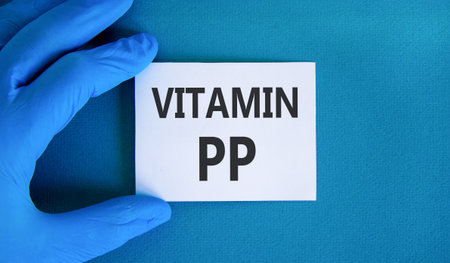 Vitamin PP symbol. Concept words Vitamin PP on beautiful white card. Doctor's hand in blue medical glove. Beautiful blue background. Medical healthy lifestyle Vitamin PP concept.の写真素材