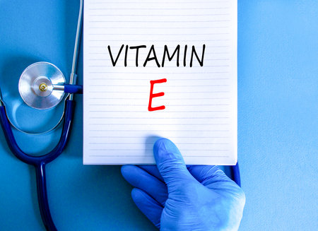 Vitamin E tocopherols symbol. Concept words Vitamin E on beautiful white note. Doctor's hand in blue medical glove. Beautiful blue background. Medical healthy lifestyle Vitamin E tocopherols concept.の写真素材