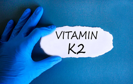 Vitamin K2 phylloquinone symbol. Concept words Vitamin K2 on beautiful paper. Doctor's hand in blue medical glove. Beautiful blue background. Medical healthy lifestyle Vitamin K2 phylloquinone conceptの写真素材