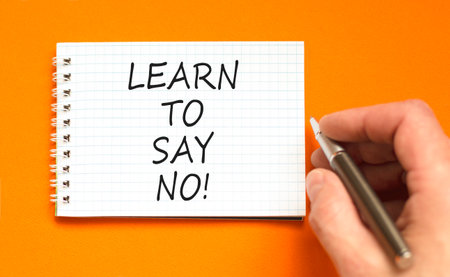 Learn to say no symbol. Concept words phrase Learn to say no on beautiful white note. Businessman's hand. Beautiful orange background. Business psychological Learn to say no concept. Copy space.の写真素材