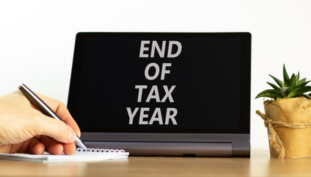 End of tax year symbol. Concept words phrase End of tax year on beautiful black tablet. Businessman's hand. Beautiful white background. Business End of tax year concept. Copy space.の写真素材