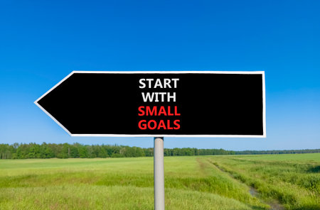 Start with small goals symbol. Concept words phrase Start with small goals on beautiful road sign. Beautiful blue sky green grass lawn background. Business Start with small goals concept. Copy space.の写真素材