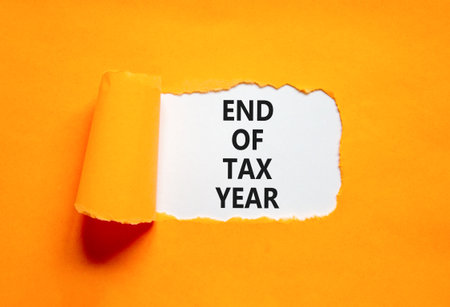 End of tax year symbol. Concept words phrase End of tax year on beautiful white paper. Beautiful orange paper background. Business End of tax year concept. Copy space.の写真素材