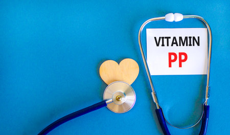 Vitamin PP symbol. Concept words Vitamin PP on beautiful white card. Wooden heart and stethoscope. Beautiful blue background. Medical healthy lifestyle Vitamin PP concept.の写真素材