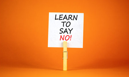 Learn to say no symbol. Concept words phrase Learn to say no on beautiful white paper on wooden clothespin. Beautiful orange paper background. Business psychological Learn to say no concept Copy spaceの写真素材