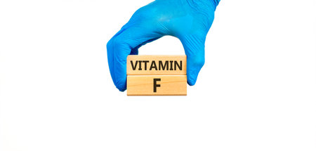 Vitamin F symbol. Concept words Vitamin F on beautiful wooden blocks. Doctor's hand in blue medical glove. Beautiful white background. Medical healthy lifestyle Vitamin F concept.の写真素材