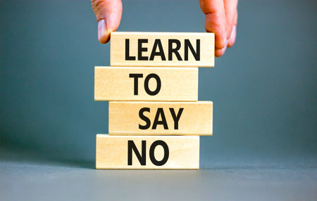 Learn to say no symbol. Concept words phrase Learn to say no on beautiful wooden blocks. Beautiful gray paper background. Businessman's hand. Business psychological Learn to say no concept. Copy spaceの写真素材