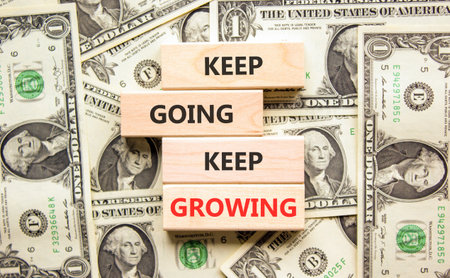 Keep going and growing symbol. Concept words phrase Keep going keep growing on beautiful wooden blocks. Dollar bills. Beautiful dollar bills background. Business Keep going growing concept. Copy spaceの写真素材
