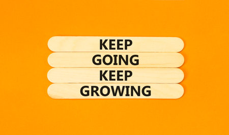 Keep going and growing symbol. Concept words phrase Keep going keep growing on beautiful wooden stick. Beautiful orange paper background. Business Keep going and growing concept. Copy space.の写真素材