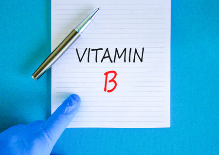Vitamin B symbol. Concept words Vitamin B on beautiful white note. Doctor's hand in blue medical glove. Black pen. Beautiful blue background. Medical healthy lifestyle Vitamin B concept.の写真素材