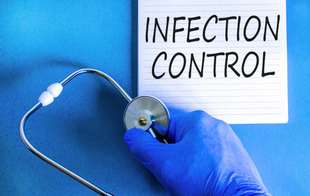 Infection control symbol. Concept words Infection control on beautiful white note. Doctor's hand in blue medical glove. Beautiful blue background. Medical healthy lifestyle infection control concept.の写真素材