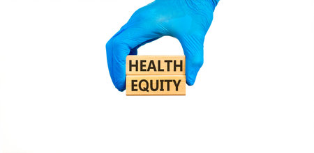 Health equity symbol. Concept words Health equity on beautiful wooden blocks. Doctor's hand in blue medical glove. Beautiful white background. Medical healthy lifestyle health equity concept.の写真素材