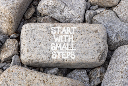Start with small steps symbol. Concept words phrase Start with small steps on beautiful gray stone. Beautiful gray stone beach background. Business Start with small steps concept. Copy space.の写真素材
