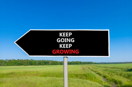 Keep going and growing symbol. Concept words phrase Keep going keep growing on beautiful road sign. Beautiful blue sky green grass lawn background. Business Keep going and growing concept. Copy space.の写真素材