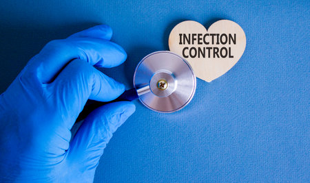Infection control symbol. Concept words Infection control on beautiful wooden heart. Doctor's hand in blue medical glove. Beautiful blue background. Medical healthy lifestyle infection control conceptの写真素材