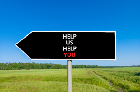 Help you symbol. Concept words phrase Help us help you on beautiful big black road sign. Beautiful blue sky green grass lawn background. Business Help you concept. Copy space.の写真素材