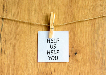 Help you symbol. Concept words phrase Help us help you on beautiful white paper on wooden clothespin. Beautiful wooden background. Business Help you concept. Copy space.の写真素材