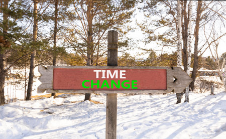 Time change symbol. Concept word Time change on beautiful wooden road sign. Beautiful snow winter forest background. Business time change concept. Copy space.の写真素材