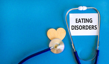 Eating disorders symbol. Concept words Eating disorders on beautiful white card. Wooden heart and...