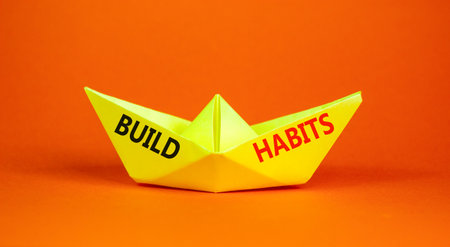 Build habits symbol. Concept word Build habits on beautiful yellow paper boat. Beautiful orange...