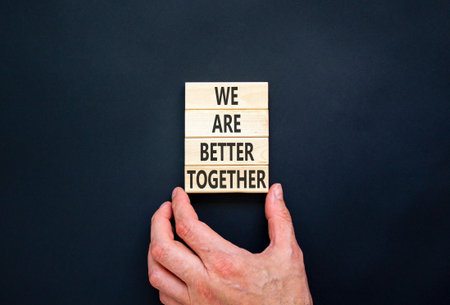 We are better together symbol. Concept words phrase We are better together on beautiful wooden blocks. Beautiful black background. Businessman hand. Business We are better together concept. Copy spaceの写真素材